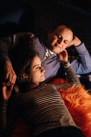 guy and girl are sitting in a wooden house on the background of a burning fireplaceの写真素材