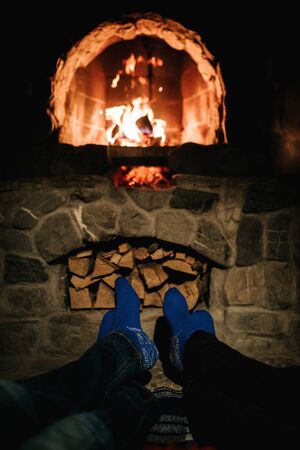 guy and girl are sitting in a wooden house on the background of a burning fireplaceの写真素材