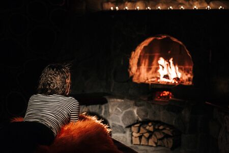 guy and girl are sitting in a wooden house on the background of a burning fireplaceの写真素材