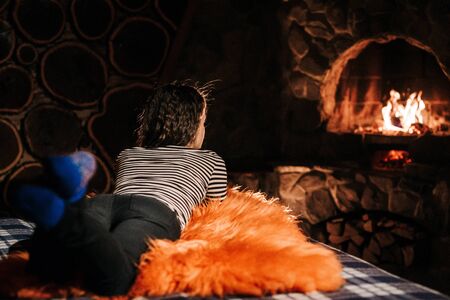 guy and girl are sitting in a wooden house on the background of a burning fireplaceの写真素材