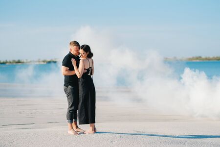guy and a girl in black clothes hug inside a white smokeの写真素材