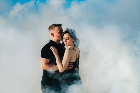 guy and a girl in black clothes hug inside a white smokeの写真素材