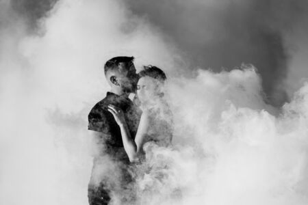 guy and a girl in black clothes hug inside a white smokeの写真素材