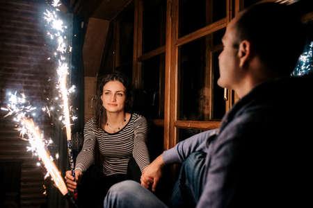 guy and a girl lit sparklers inside a wooden house late at night