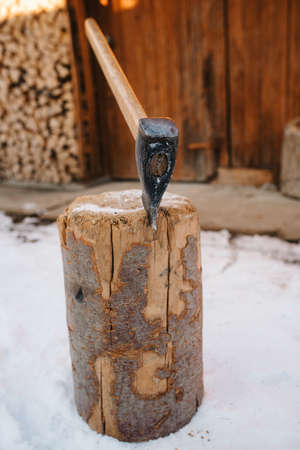 guy in winter clothes chopping wood in the yard, covered with snowの写真素材