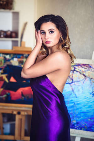 model girl in a blue dress in an art workshop with brushes, a palette and paintingsの写真素材