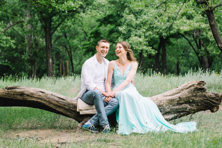 happy guy in a white shirt and a girl in a turquoise dress, the bride and groom are walking in the forest parkの写真素材