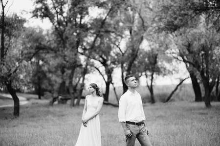 happy guy in a white shirt and a girl in a turquoise dress, the bride and groom are walking in the forest parkの写真素材