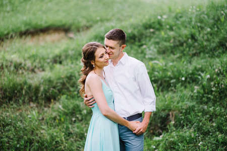 happy guy in a white shirt and a girl in a turquoise dress, the bride and groom are walking in the forest parkの写真素材