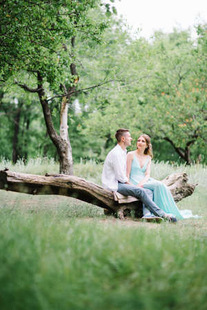 happy guy in a white shirt and a girl in a turquoise dress, the bride and groom are walking in the forest parkの写真素材