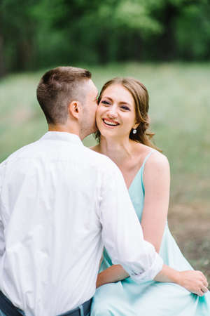happy guy in a white shirt and a girl in a turquoise dress, the bride and groom are walking in the forest parkの写真素材