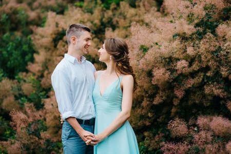 happy guy in a white shirt and a girl in a turquoise dress, the bride and groom are walking in the forest parkの写真素材