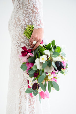 joyful girl bride in a white knitted dress posing with a bouquet of flowers in the studio on a white backgroundの写真素材