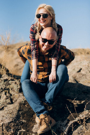 Guy and girl in caged shirts and trekking shoes on garnit rocksの写真素材