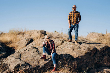 Guy and girl in caged shirts and trekking shoes on garnit rocksの写真素材