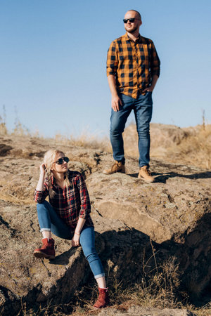 Guy and girl in caged shirts and trekking shoes on garnit rocksの写真素材