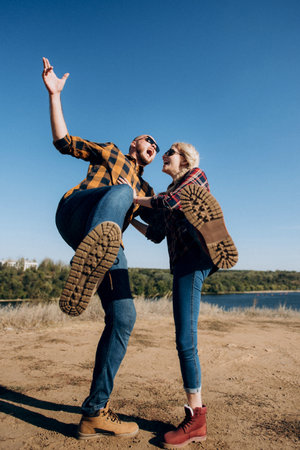Guy and girl in caged shirts and trekking shoes on garnit rocksの写真素材