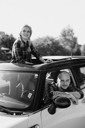 traveling by car of a young couple of a guy and a girl in plaid shirtsの写真素材
