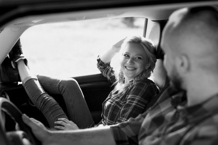 traveling by car of a young couple of a guy and a girl in plaid shirtsの写真素材