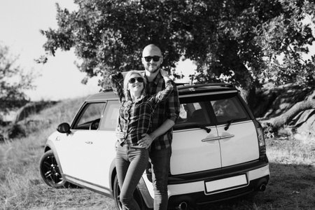 traveling by car of a young couple of a guy and a girl in plaid shirtsの写真素材