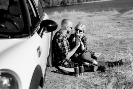 traveling by car of a young couple of a guy and a girl in plaid shirtsの写真素材