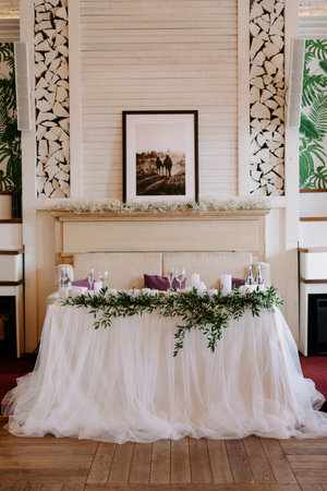 the presidium of the newlyweds in the banquet hall of the restaurant is decorated with candles and green plants, the general tone of the hall is beigeの写真素材