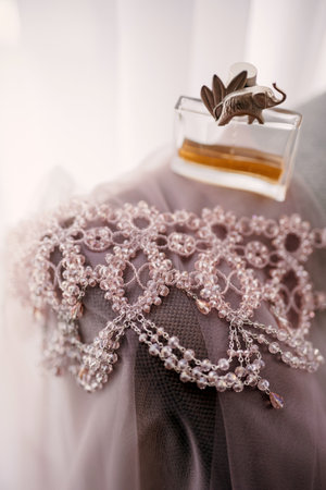 elegant bottle of perfume on the armchair with a pink necklace of the brideの写真素材