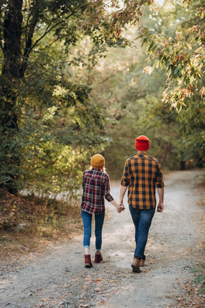 Cheerful guy and girl on a walk in bright knitted hats and plaid shirtsの写真素材