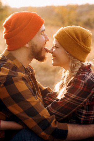 Cheerful guy and girl on a walk in bright knitted hats and plaid shirtsの写真素材