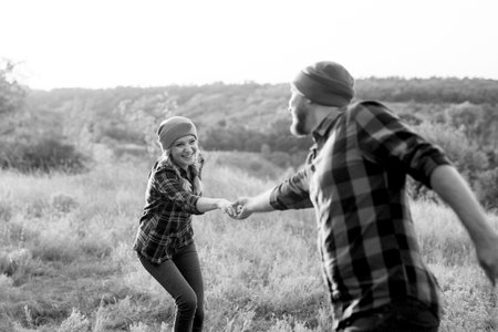 Cheerful guy and girl on a walk in bright knitted hats and plaid shirtsの写真素材