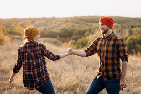 Cheerful guy and girl on a walk in bright knitted hats and plaid shirtsの写真素材