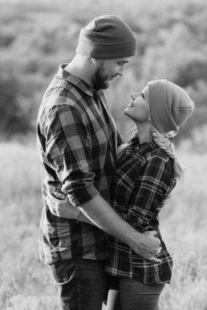 Cheerful guy and girl on a walk in bright knitted hats and plaid shirtsの写真素材