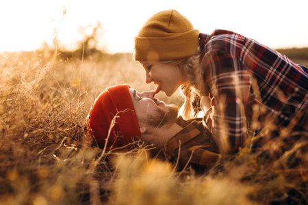 Cheerful guy and girl on a walk in bright knitted hats and plaid shirtsの写真素材
