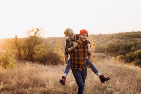 Cheerful guy and girl on a walk in bright knitted hats and plaid shirtsの写真素材