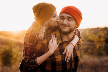 Cheerful guy and girl on a walk in bright knitted hats and plaid shirtsの写真素材