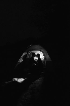Young couple a guy and a girl in bright knitted hats stopped at a camping near the fireの写真素材