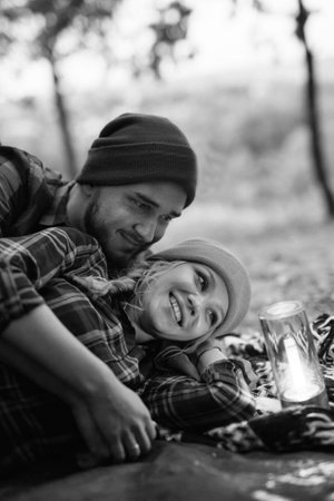 Young couple a guy and a girl in bright knitted hats stopped at a camping near the fireの写真素材