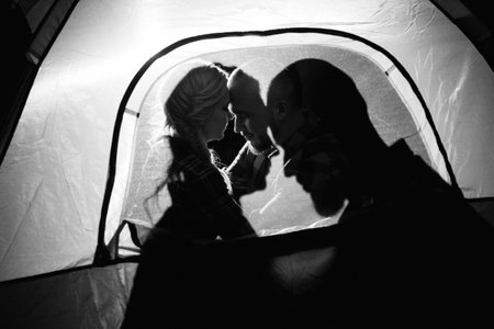 Young couple a guy and a girl in bright knitted hats stopped at a camping near the fireの写真素材