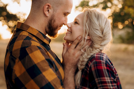Cheerful guy with a board and a blonde girl for a walk in plaid shirts at sunsetの写真素材
