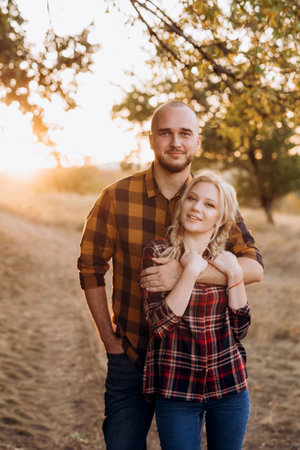 Cheerful guy with a board and a blonde girl for a walk in plaid shirts at sunsetの写真素材