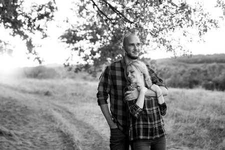 Cheerful guy with a board and a blonde girl for a walk in plaid shirts at sunsetの写真素材