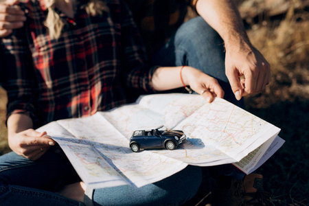 Bald guy with a beard and a blonde girl are looking at the map and looking for a route to travelの写真素材
