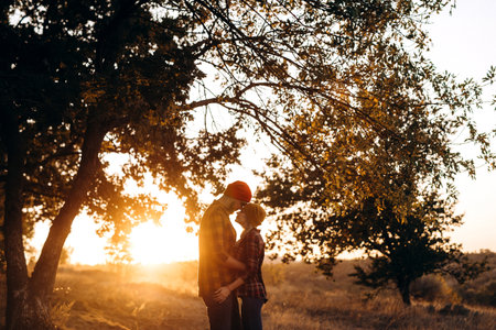 Cheerful guy with a board and a blonde girl for a walk in plaid shirts at sunsetの写真素材