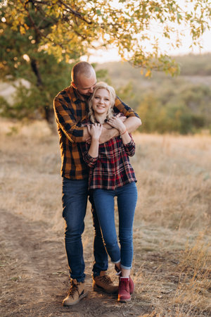 Cheerful guy with a board and a blonde girl for a walk in plaid shirts at sunsetの写真素材