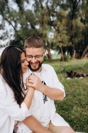 young couple in love a guy with a beard and a girl with dark hair in light clothes in the green forestの写真素材