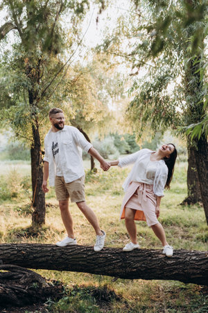 young couple in love a guy with a beard and a girl with dark hair in light clothes in the green forestの写真素材