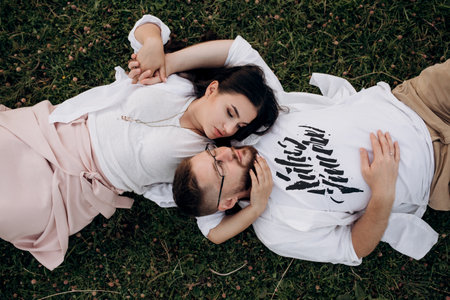 young couple in love a guy with a beard and a girl with dark hair in light clothes in the green forestの写真素材