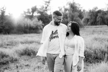 young couple in love a guy with a beard and a girl with dark hair in light clothes in the green forestの写真素材