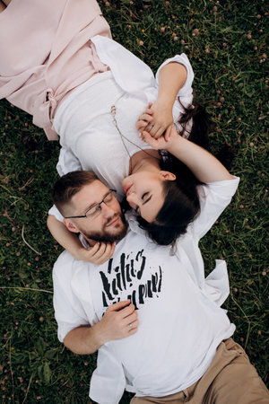young couple in love a guy with a beard and a girl with dark hair in light clothes in the green forestの写真素材