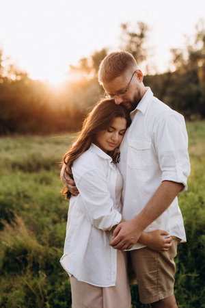 young couple in love a guy with a beard and a girl with dark hair in light clothes in the green forestの写真素材